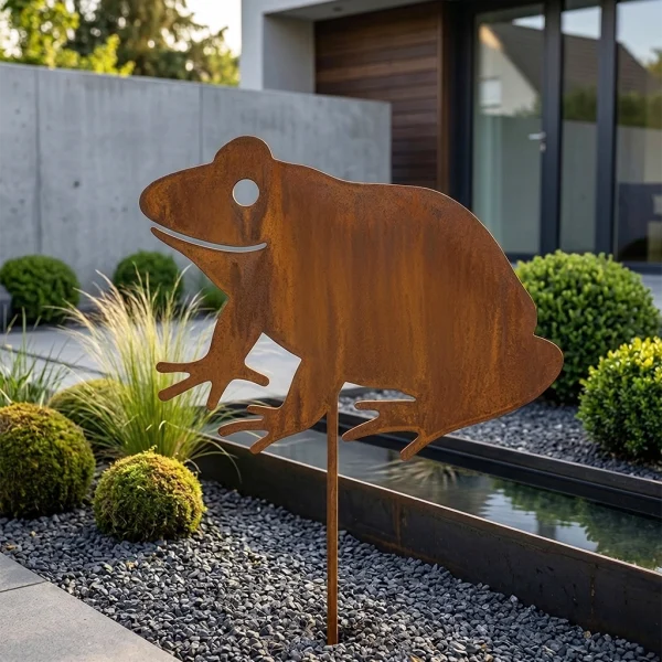dekoracja ogrodowa 1025 Żaba Metal4Home – metalowa żaba corten ustawiona przy oczku wodnym w ogrodzie z kamieniami i roślinnością